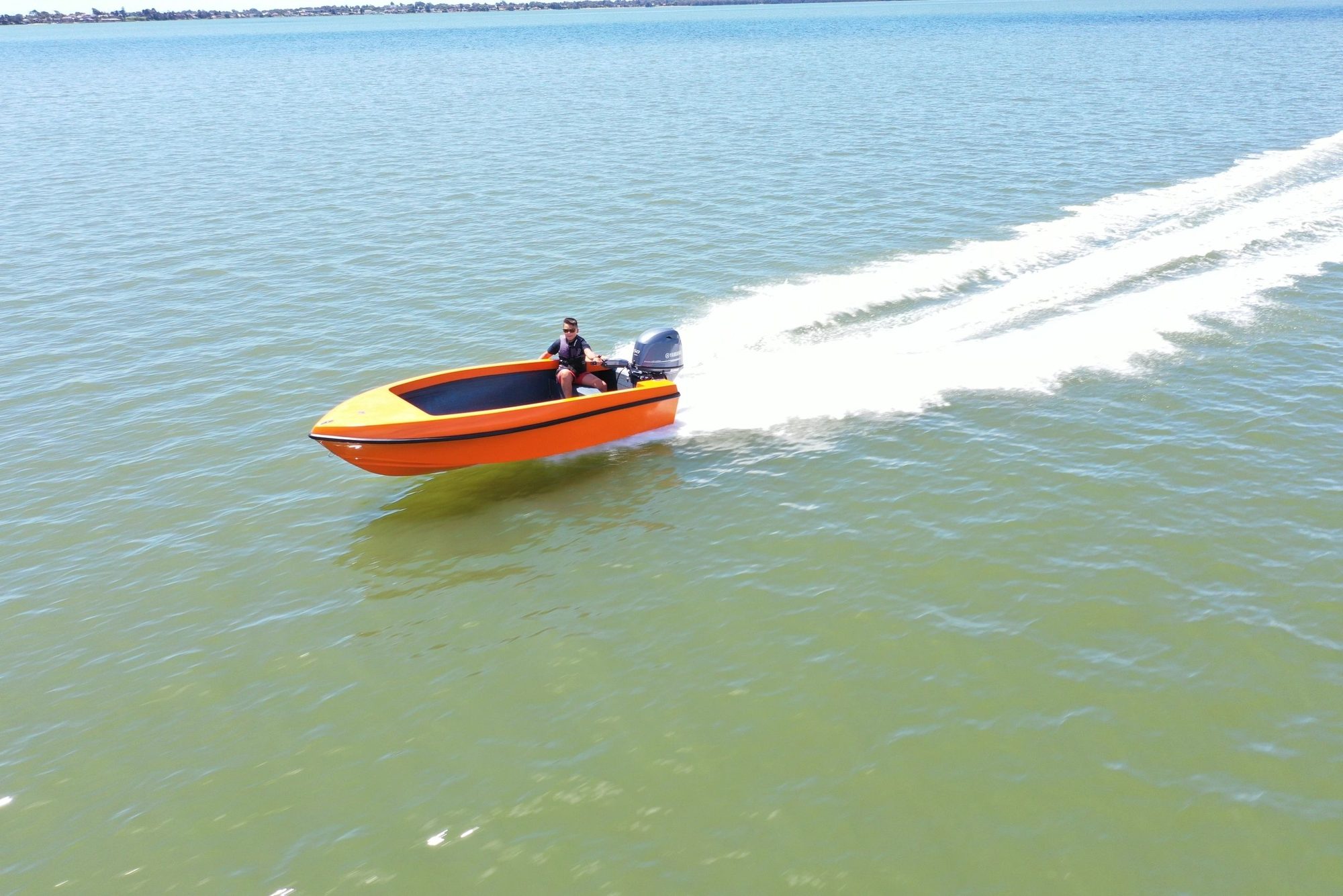 Orange and white Mighty Boy cruising across the lake with the skipper at the tiller