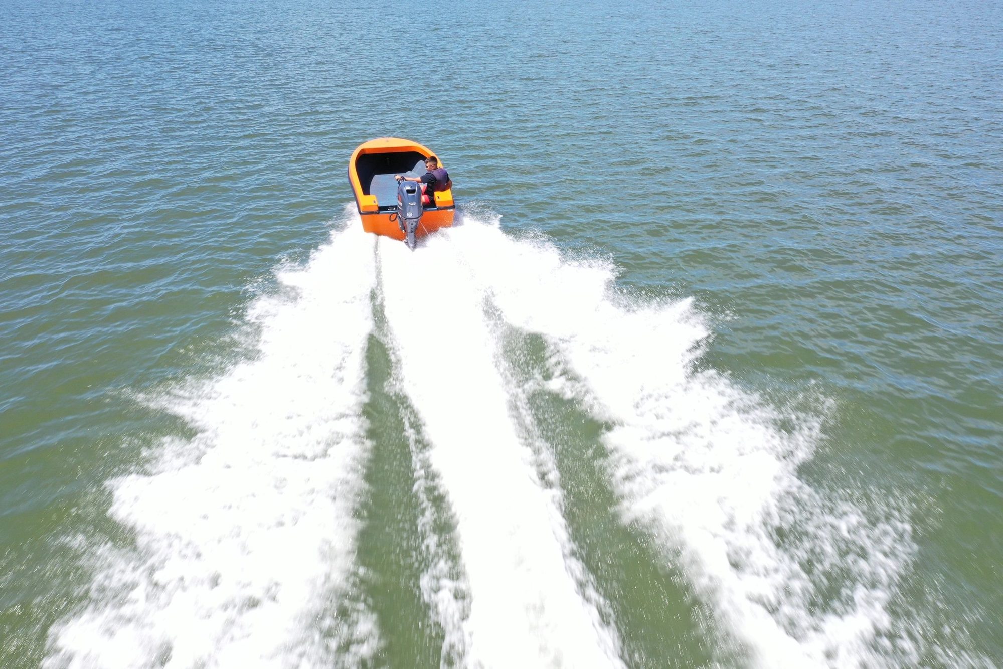 Mighty Boy pulling a wide white wake on green water