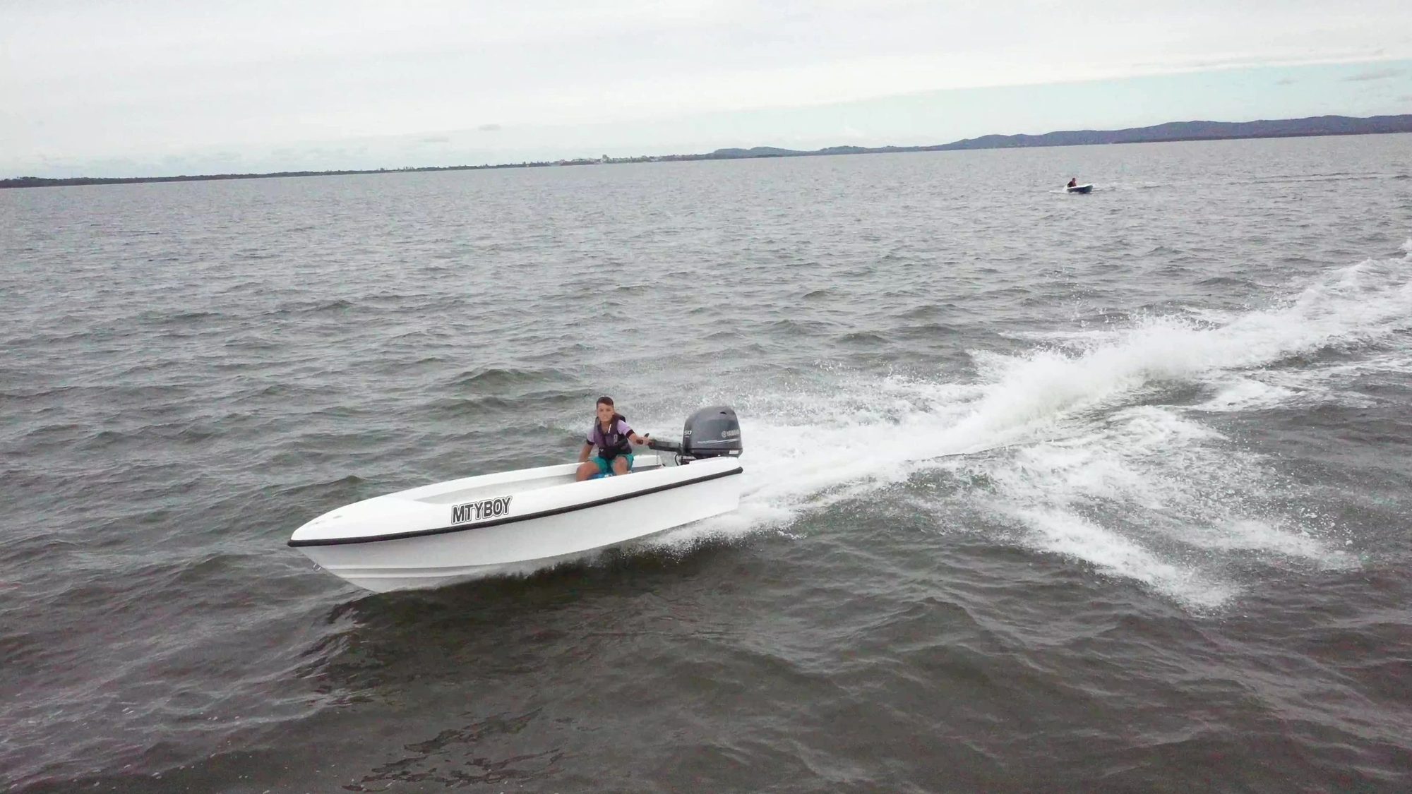 White Mighty Boy running flat across the water, wake trailing behind