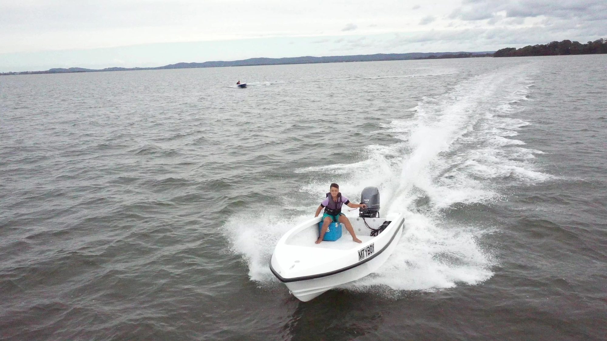 White Mighty Boy carving a turn with spray off the side